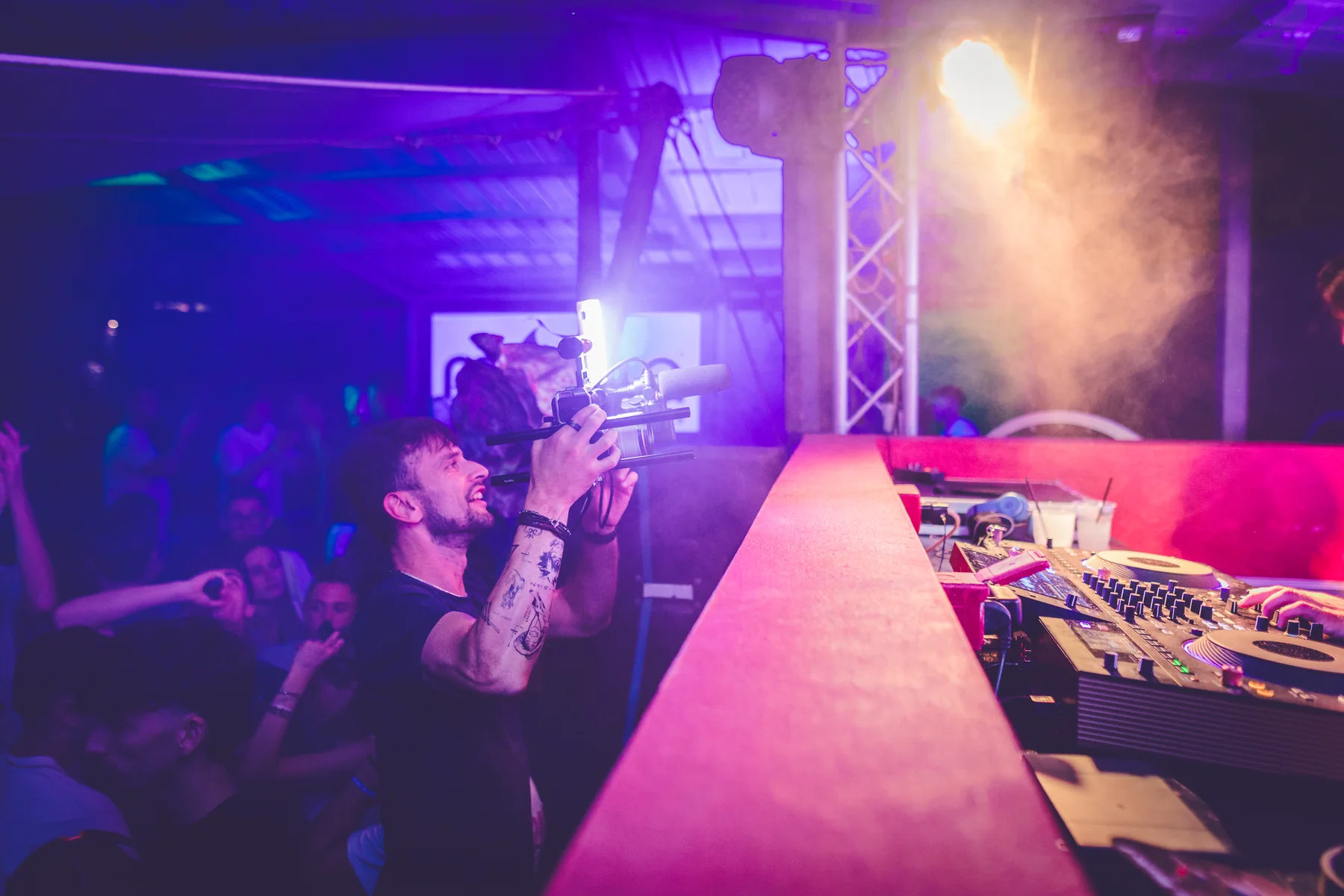Riprese video accanto a una postazione DJ, sotto luci viola